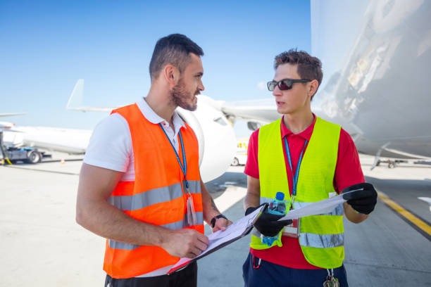 istock Airport service crew in front of airplane, checking documents 1202299810