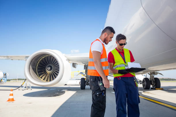 istock Airport service crew in front of airplane, checking documents 1202299895