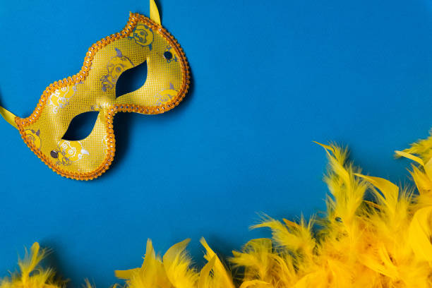 istock Yellow mask and feather boa, cape, carnival costume, on blue background 1202300185
