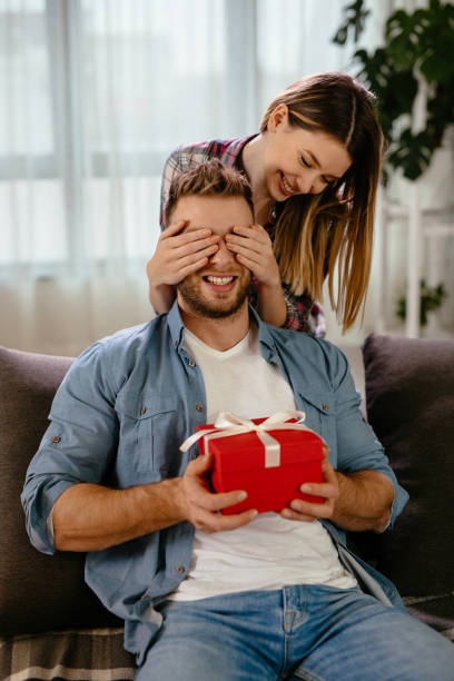 istock Young woman surprising her boyfriend with gift 1202300206
