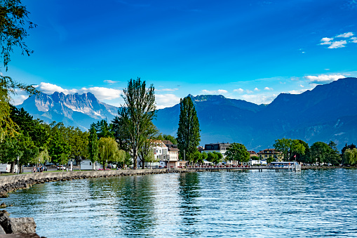 Tourists beside Lake Geneva, Switzerland.  In the background is Lake Geneva and the Swiss Alps. Near Nyon.
