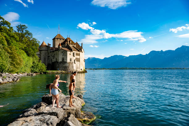 Tourists beside Chateau de Chillon on Lake Geneva, Switzerland.  In the background is Lake Geneva and the Swiss Alps.