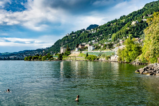 Tourists beside Lake Geneva, Switzerland.  In the background is Lake Geneva and the Swiss Alps. Near Nyon.