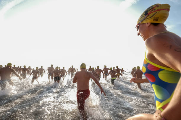 uma multidão de nadadores correndo para a água depois de uma competição em águas abertas tinha começado - triathlon ironman triathalon ironman people - fotografias e filmes do acervo