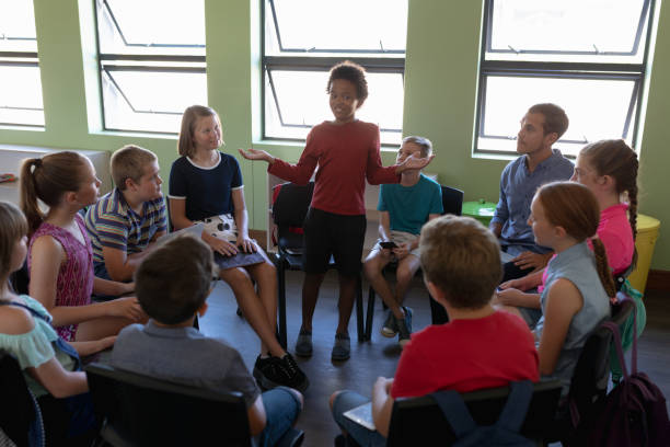 gruppe von grundschulkindern im kreis sitzend - darstellung stock-fotos und bilder