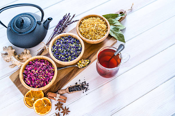 istock Herbal tea cup with various multi colored dried tea leaves and flowers shot on white table 1202306430