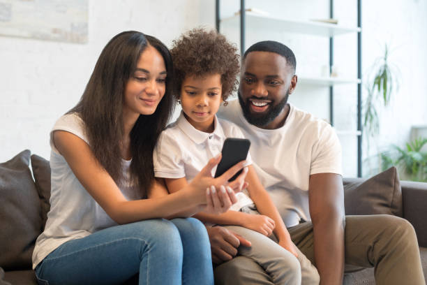 istock Smiling young family looking at smartphone screen at home 1202308612