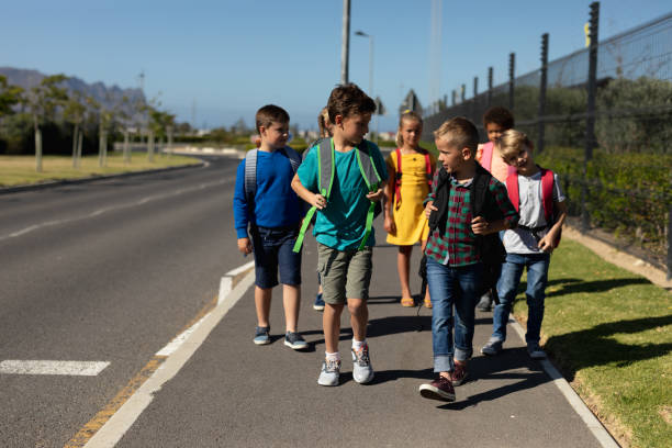 istock Group of elementary school pupils walking along a road 1202308642