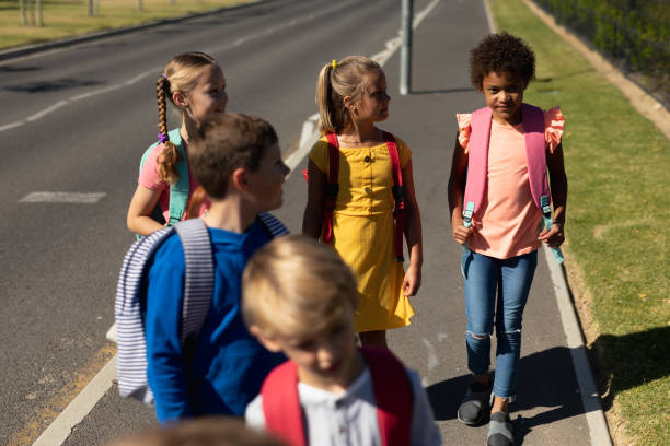 istock Group of elementary school pupils walking along a road 1202308656