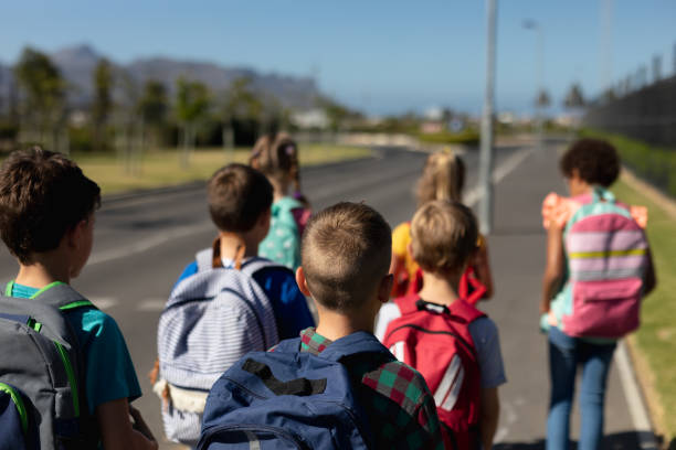 istock Group of elementary school pupils walking along a road 1202308661