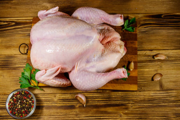istock Raw whole chicken with spices on a wooden table. Top view 1202308675
