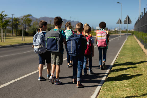 istock Group of elementary school pupils walking along a road 1202308680