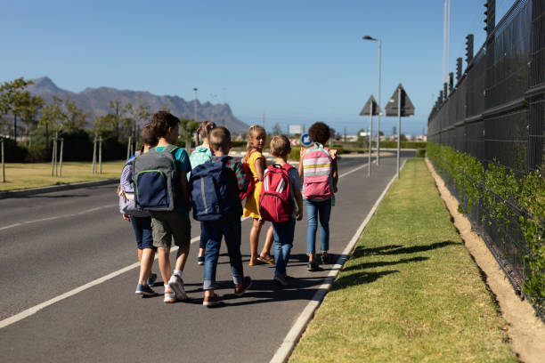 istock Group of elementary school pupils walking along a road 1202308685