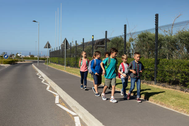 istock Group of elementary school pupils walking along a road 1202308691