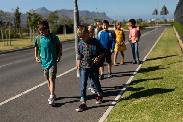 istock Group of elementary school pupils walking along a road 1202308700