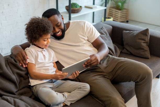 istock Smiling father and his son using tablet at home 1202309018