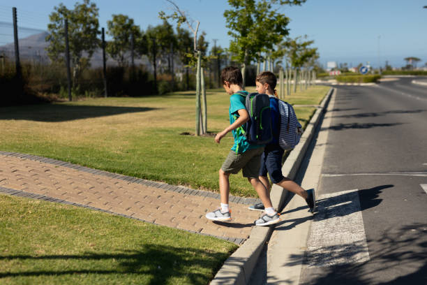 istock Two schoolboys reaching the pavement after crossing the road 1202309980