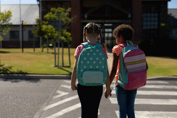 istock Two schoolgirls looking for traffic while waiting to cross the road 1202310021