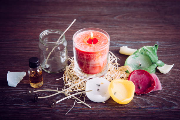 istock Reusing old candles leftovers and making melting a new one: various ingredients on table: candle wicks, glass jar, old candles wax, aroma oil. New candle in glass in center. 1202310418