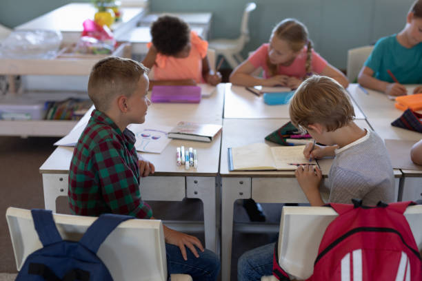 istock Schoolboys sitting at desks in an elementary school classroom 1202312253