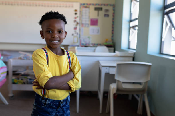 istock Schoolboy standing with arms crossed in an elementary school classroom 1202312368