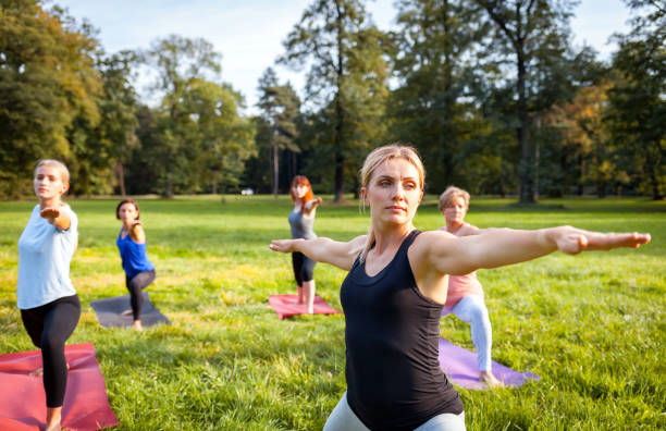 istock Mixed age group of people practicing yoga outside in the park 1202312689