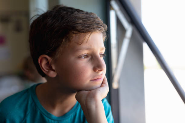 istock Schoolboy looking out of an open window in an elementary school classroom 1202313669