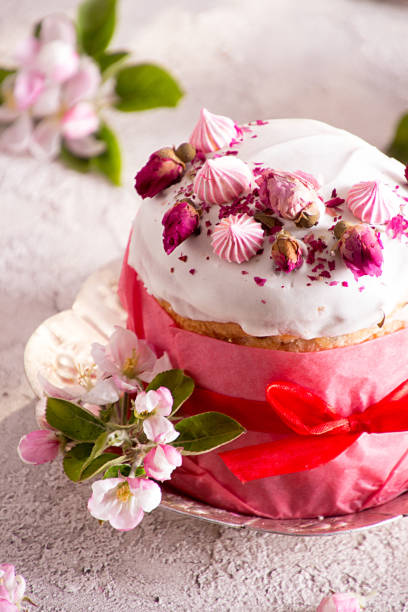 istock Happy Easter decoration for greeting card. Easter cake with white icing, marshmallows, dry rose and fresh blooming apple flowers and rose color craft paper on gauze background.. 1202313785