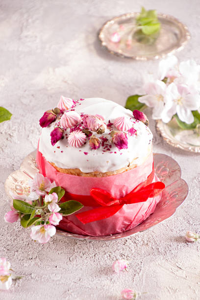 istock Happy Easter decoration for greeting card. Easter cake with white icing, marshmallows, dry rose and fresh blooming apple flowers and rose color craft paper on gauze background.. 1202313890
