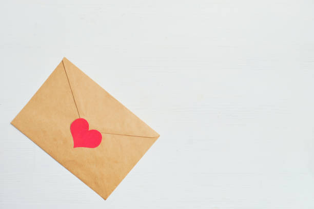 istock Red heart with a craft envelope on a white wooden background. Copy space. 1202313915