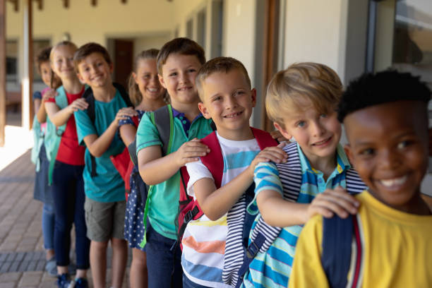 Group of schoolchildren walking single file with hands on each others at an elementary school