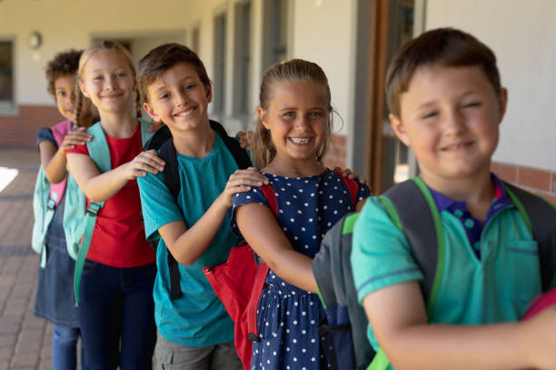 istock Group of schoolchildren walking single file with hands on each others at an elementary school 1202314068