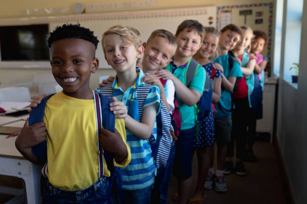 istock Group of schoolchildren walking single file with hands on each others at an elementary school 1202314082