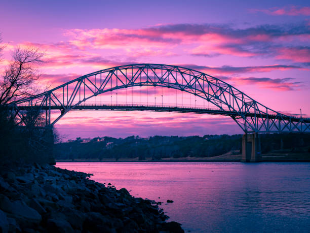 Sagamore Bridge over the Cape Cod Canal under a purple twilight sky long exposure photo bridge crossing cloud built structure stock pictures, royalty-free photos & images