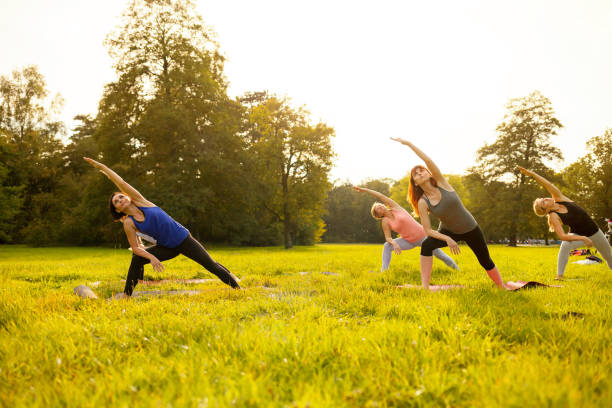 istock Mixed age group of people practicing yoga outside in the park while sunset 1202316622