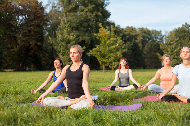 istock Mixed age group of people practicing yoga outside in the park 1202316824