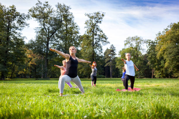 istock Mixed age group of people practicing yoga outside in the park 1202317291