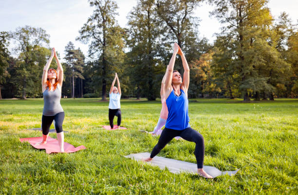istock Mixed age group of people practicing yoga outside in the park 1202317338