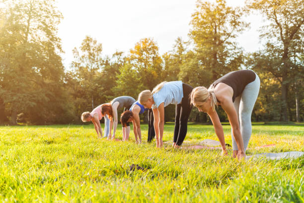 istock Mixed age group of people practicing yoga outside in the park 1202317454