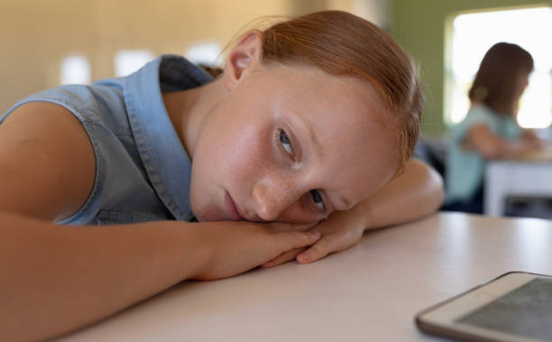 istock Schoolgirl leaning on her desk in an elementary school classroom 1202318390