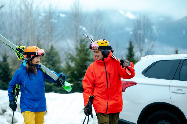 Couple getting ready for skiing from their car Mixed race couple going skiing. Adult ski vacations. Active lifestyle with a car. ski holiday stock pictures, royalty-free photos & images