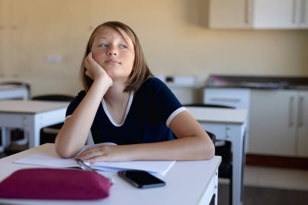 istock Schoolgirl sitting at a desk in an empty elementary school classroom 1202319951