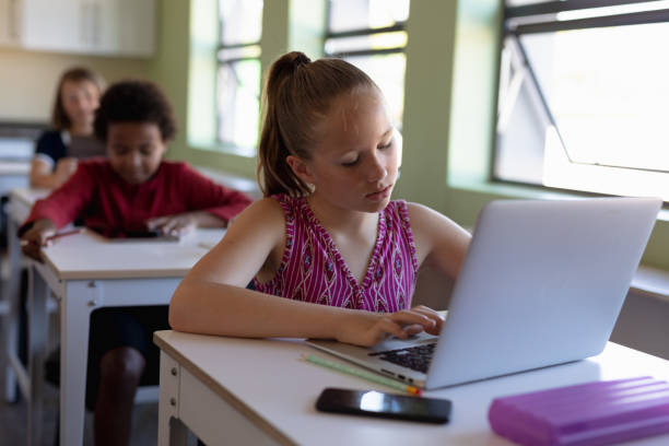istock Schoolgirl sitting at a desk using a laptop computer 1202319966