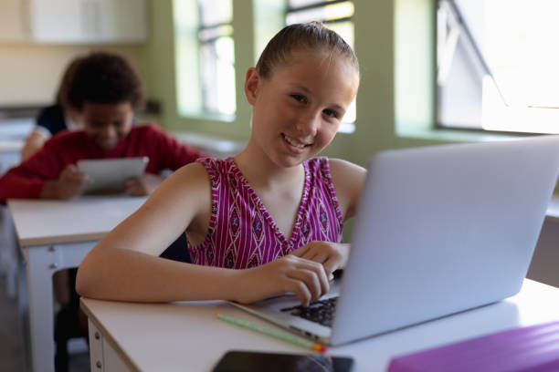 istock Schoolgirl sitting at a desk using a laptop computer 1202319977