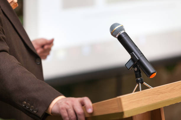 istock A man stands a with a microphone and holds a conference 1202320272