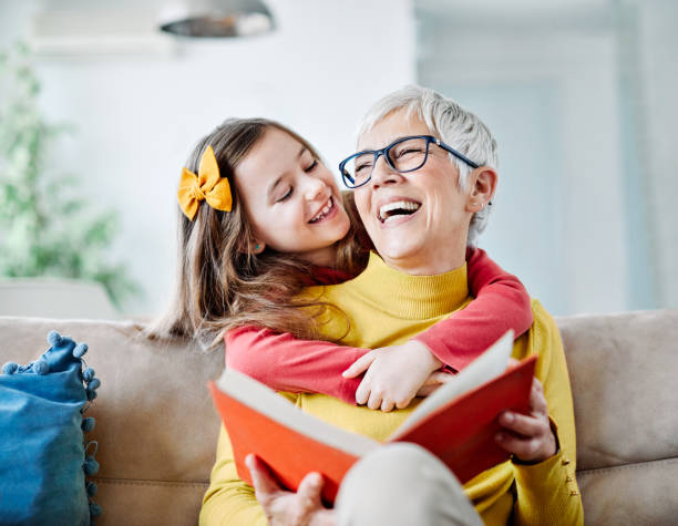 grandchild granddaughter grandma grandmother reading book girl senior Grandmother and granddaughter having fun together and reading a book at home young grandparents stock pictures, royalty-free photos & images