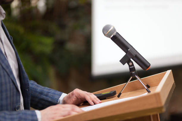 istock A man stands a with a microphone and holds a conference 1202320959