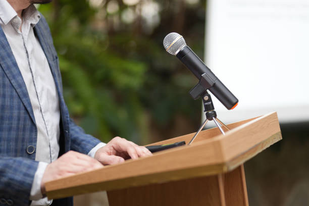 istock A man stands a with a microphone and holds a conference 1202321117