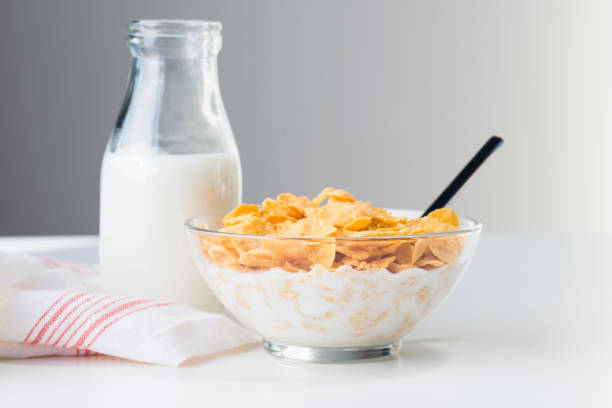 Snack Bowl of corn flakes with milk and a bottle of milk on white background. corn flakes stock pictures, royalty-free photos & images