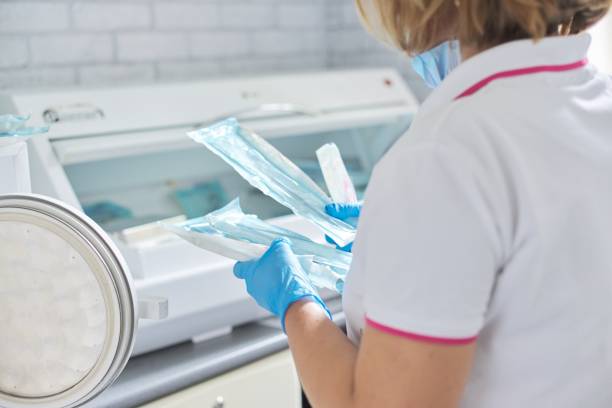 weibliche krankenschwester tun sterilisation von zahnmedizinischen instrumenten im autoklaven - dental hygiene laboratory dental equipment technician stock-fotos und bilder